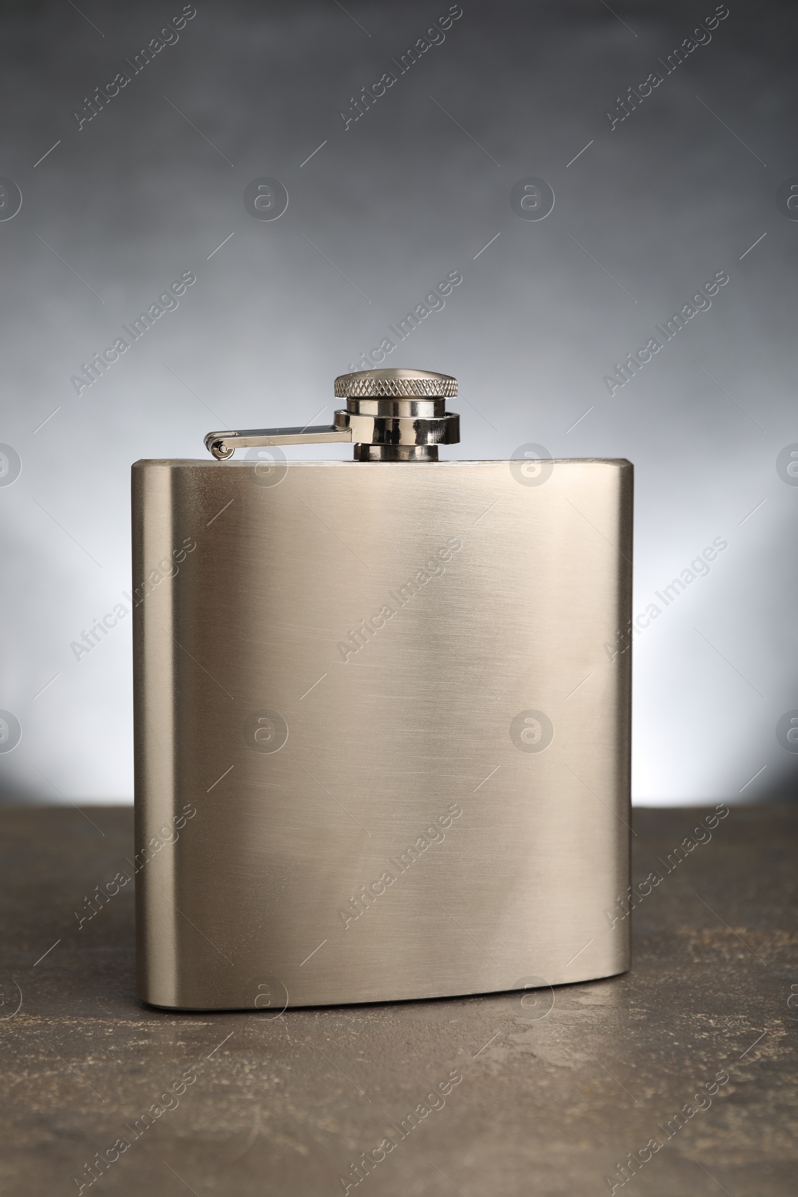 Photo of One stainless steel hip flask on grey table