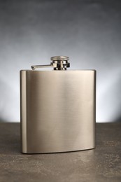 Photo of One stainless steel hip flask on grey table