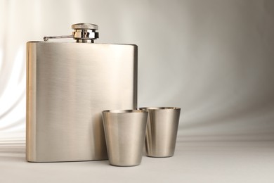 Photo of Hip flask and cups on light table, space for text