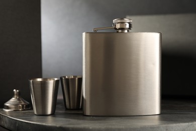 Photo of Hip flask, cups and funnel on table, closeup