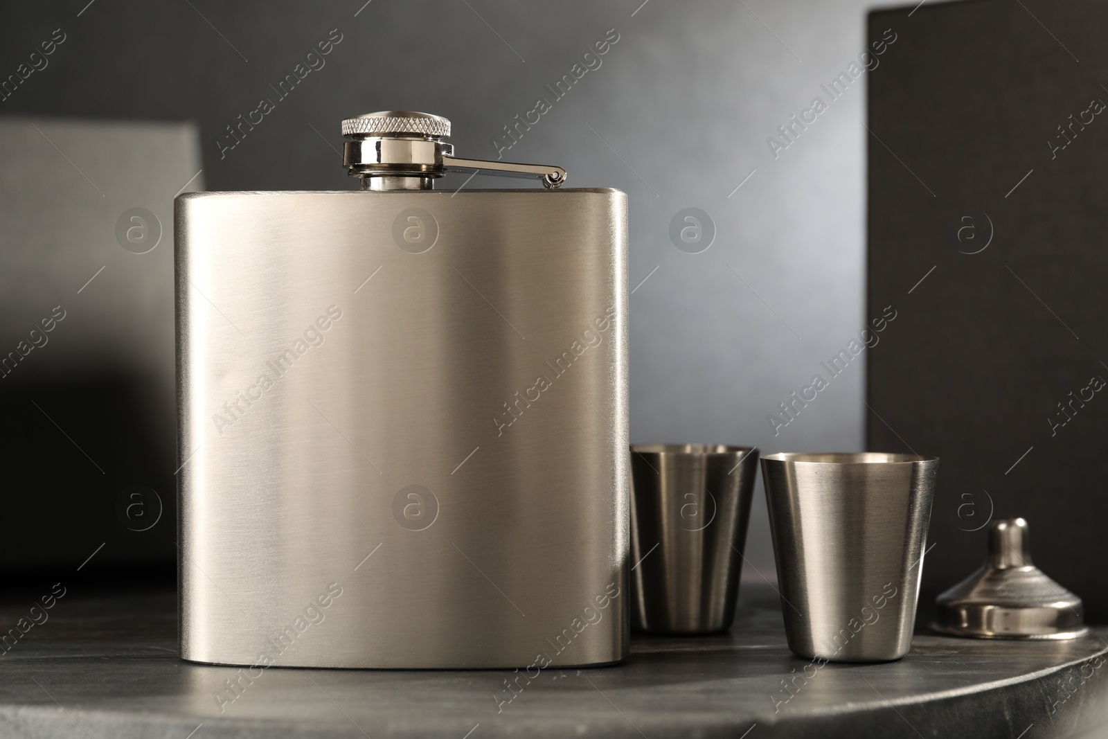 Photo of Hip flask, cups and funnel on table, closeup