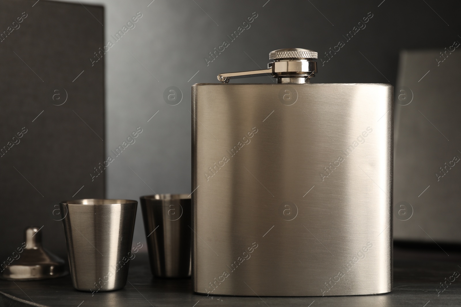 Photo of Hip flask, cups and funnel on table, closeup