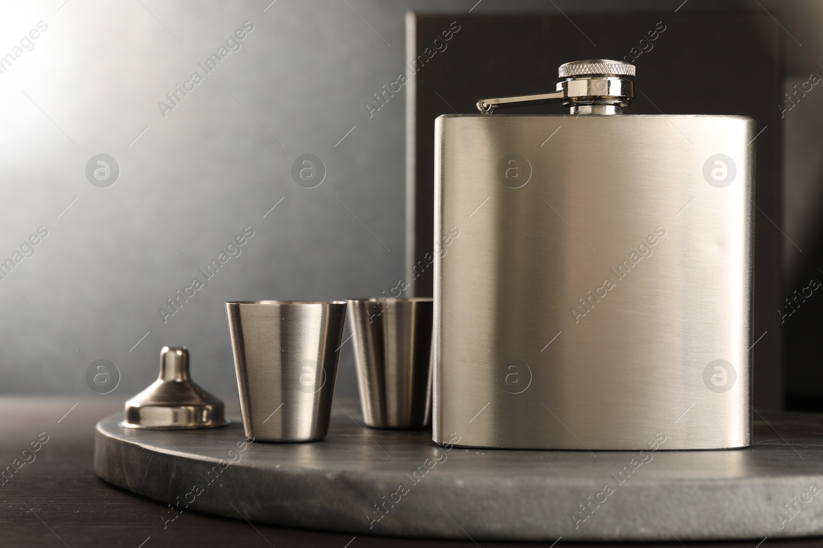 Photo of Hip flask, cups and funnel on wooden table, closeup