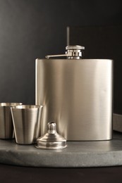 Photo of Hip flask, cups and funnel on table, closeup