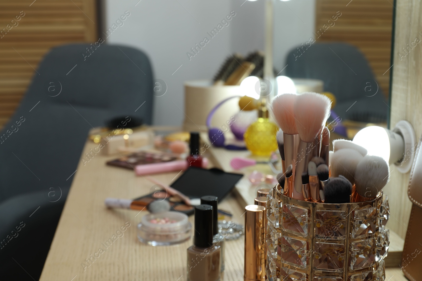 Photo of Makeup room. Different beauty products on wooden dressing table indoors, closeup