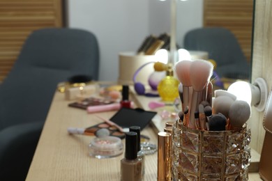 Photo of Makeup room. Different beauty products on wooden dressing table indoors, closeup