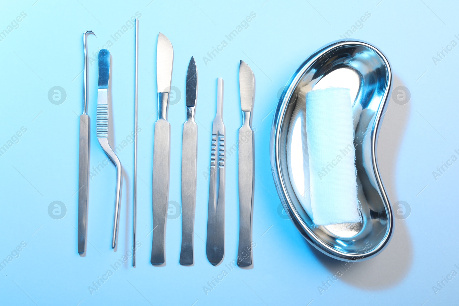 Photo of Different surgical instruments on light blue background, flat lay