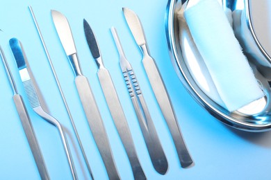 Photo of Different surgical instruments on light blue background, flat lay