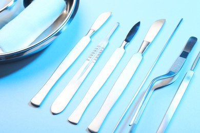 Photo of Different surgical instruments on light blue background, closeup