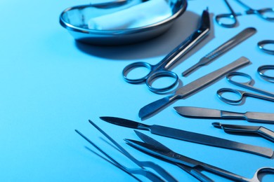 Photo of Different surgical instruments on light blue background, closeup. Space for text