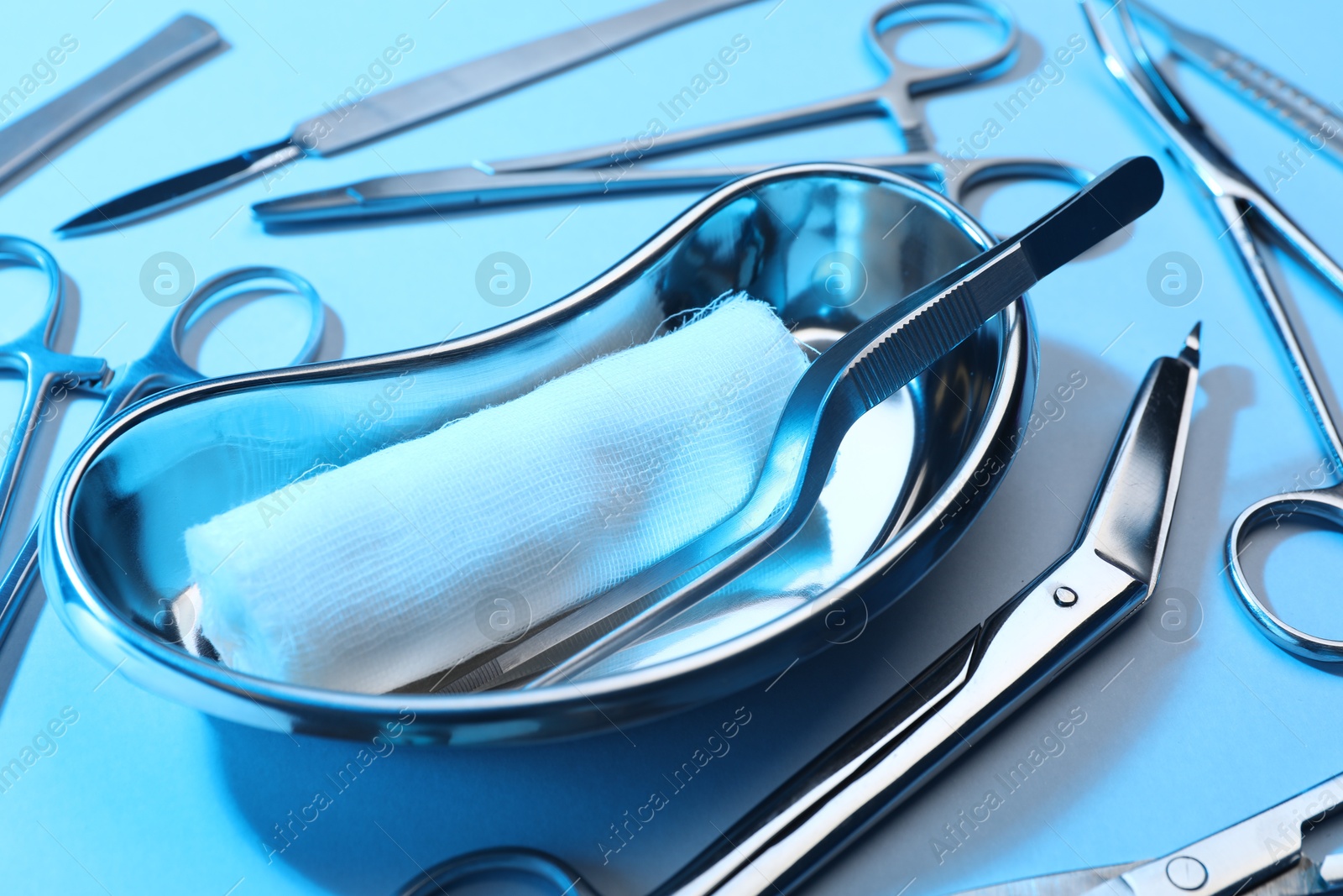 Photo of Different surgical instruments on light blue background, closeup