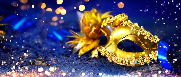 Image of Beautiful carnival mask on dark blue background with glitter, bokeh effect. Banner design with space for text