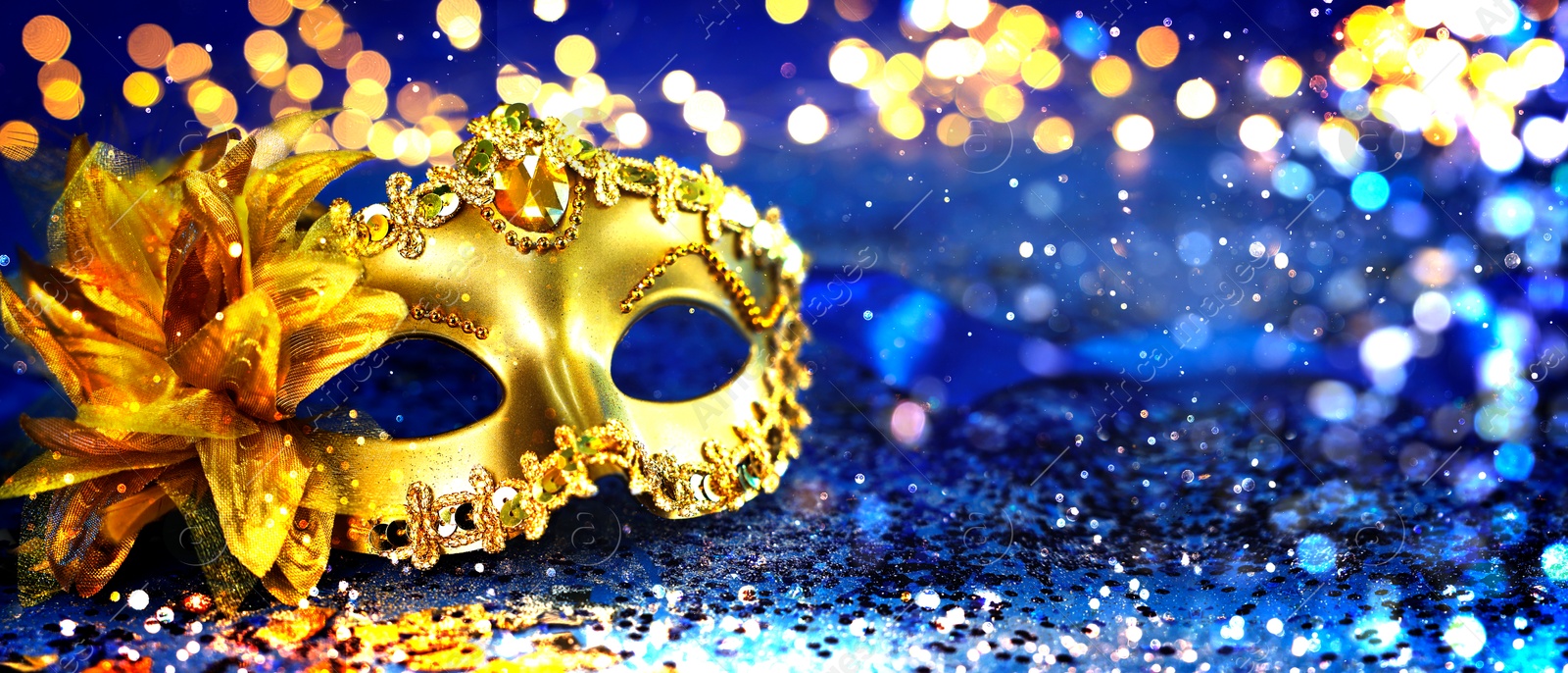 Image of Beautiful carnival mask on dark blue background with glitter, bokeh effect. Banner design with space for text