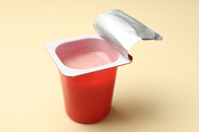 Photo of Delicious yogurt in plastic cup on beige background, closeup