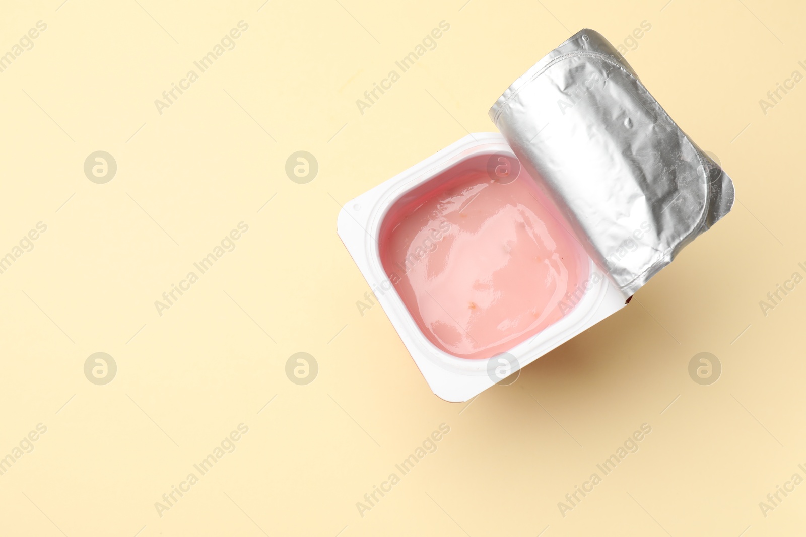 Photo of Delicious yogurt in plastic cup on beige background, top view. Space for text