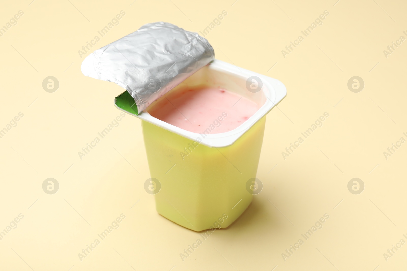 Photo of Delicious yogurt in plastic cup on beige background, closeup