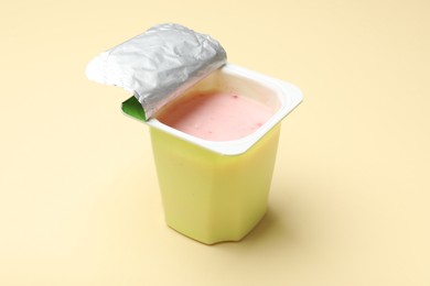 Photo of Delicious yogurt in plastic cup on beige background, closeup