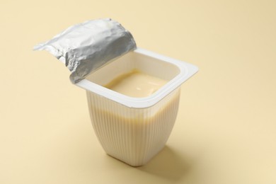 Photo of Delicious yogurt in plastic cup on beige background, closeup