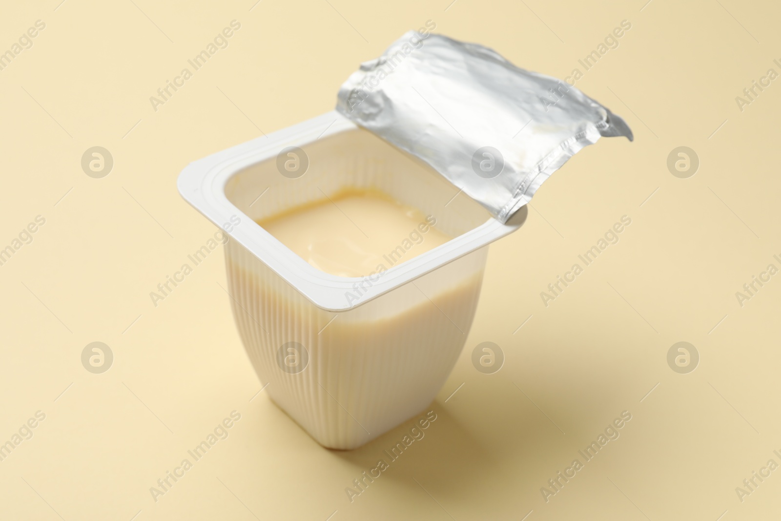 Photo of Delicious yogurt in plastic cup on beige background, closeup