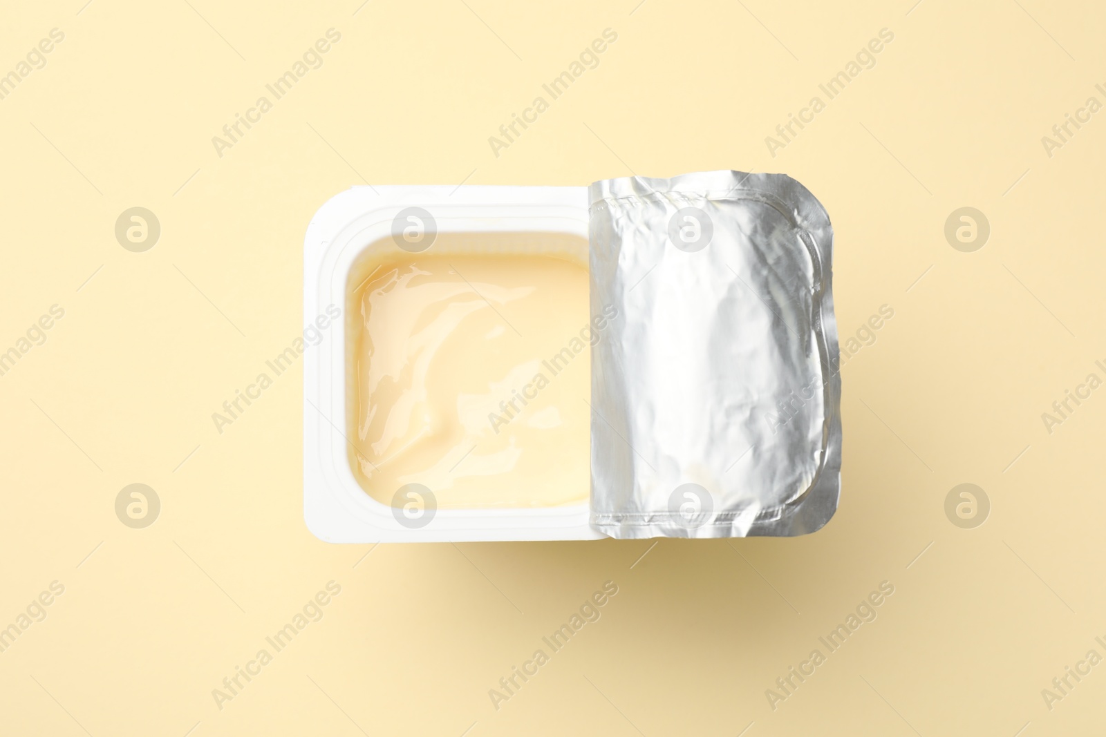 Photo of Delicious yogurt in plastic cup on beige background, top view