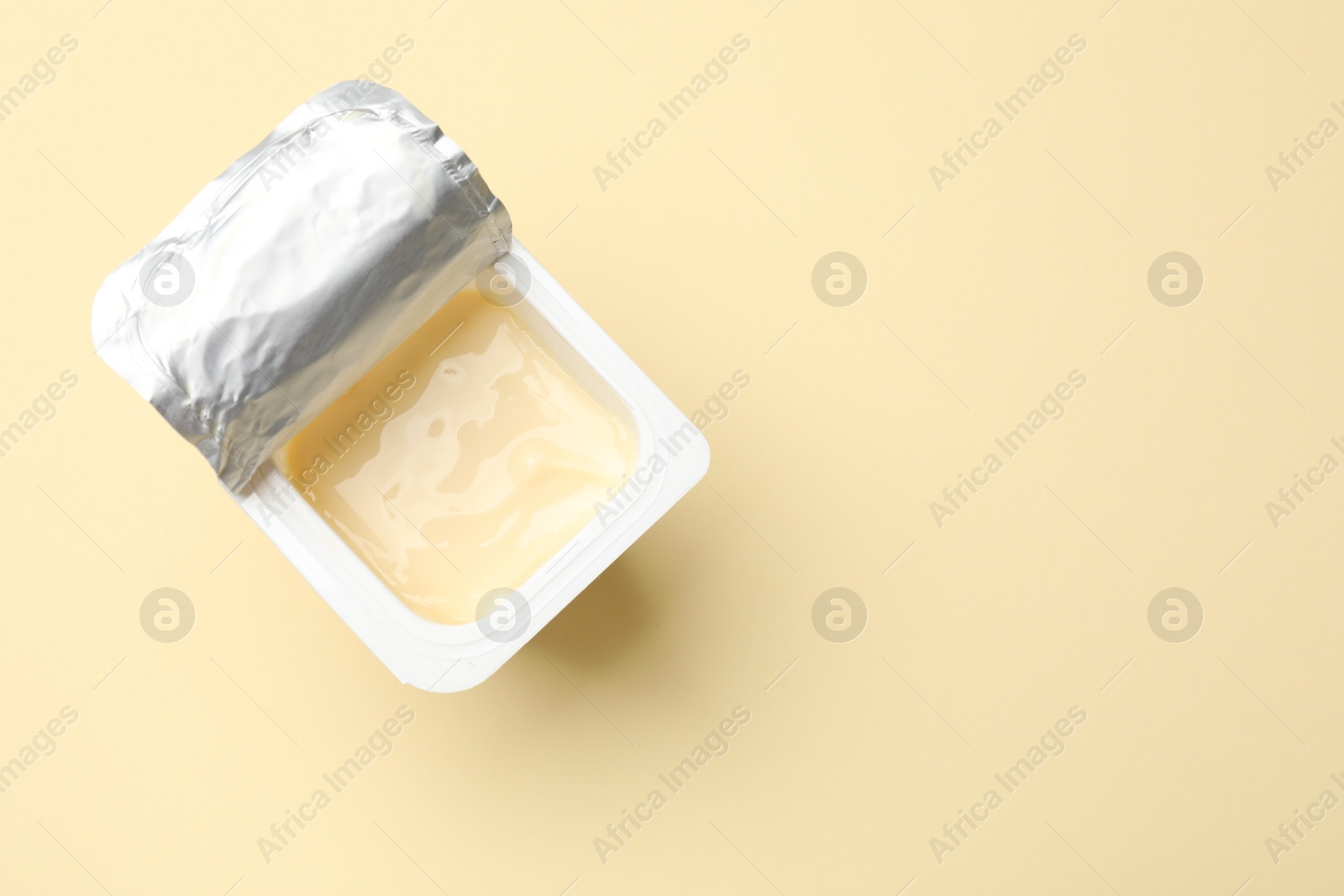 Photo of Delicious yogurt in plastic cup on beige background, top view. Space for text