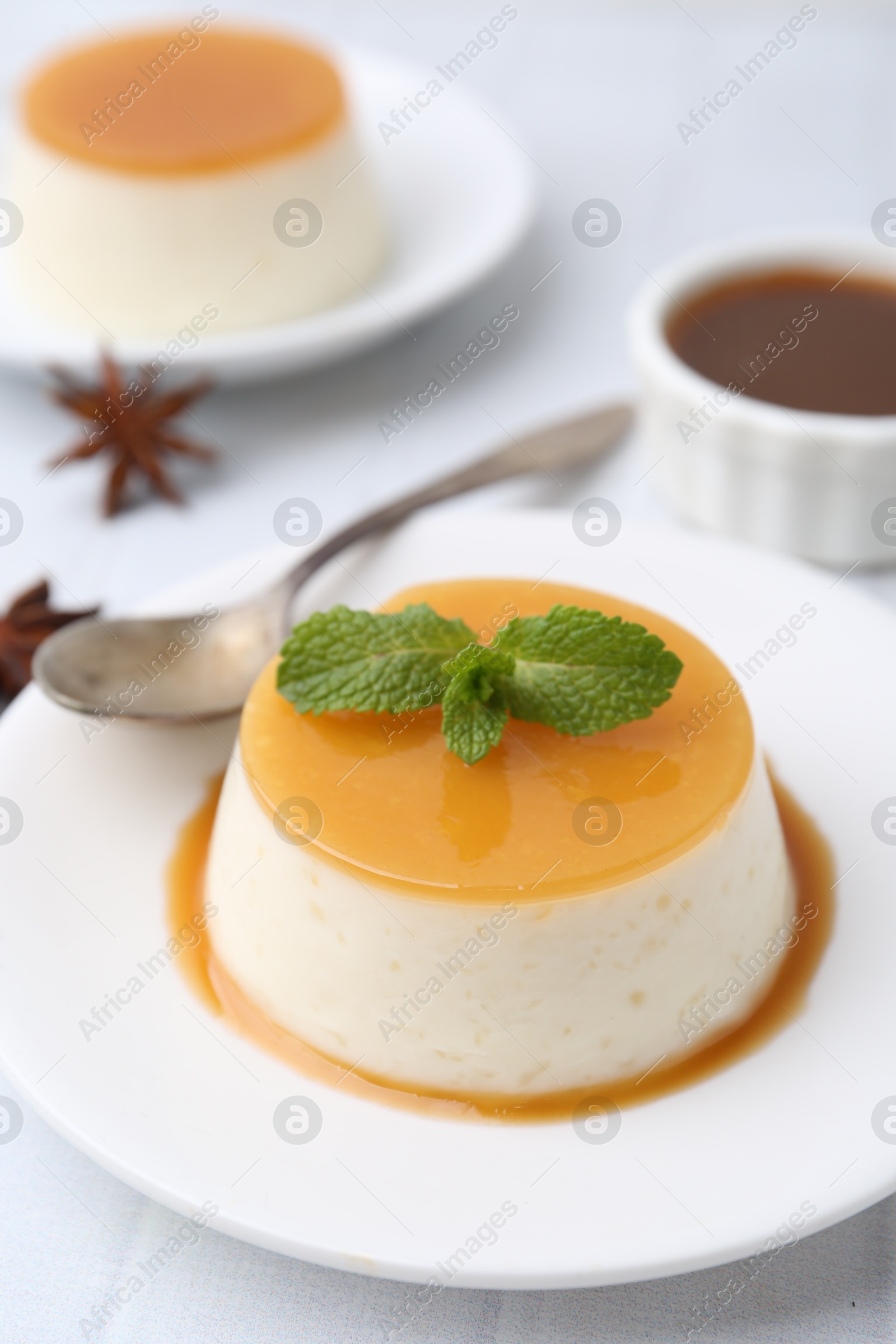 Photo of Tasty pudding with caramel sauce served on white tiled table, closeup