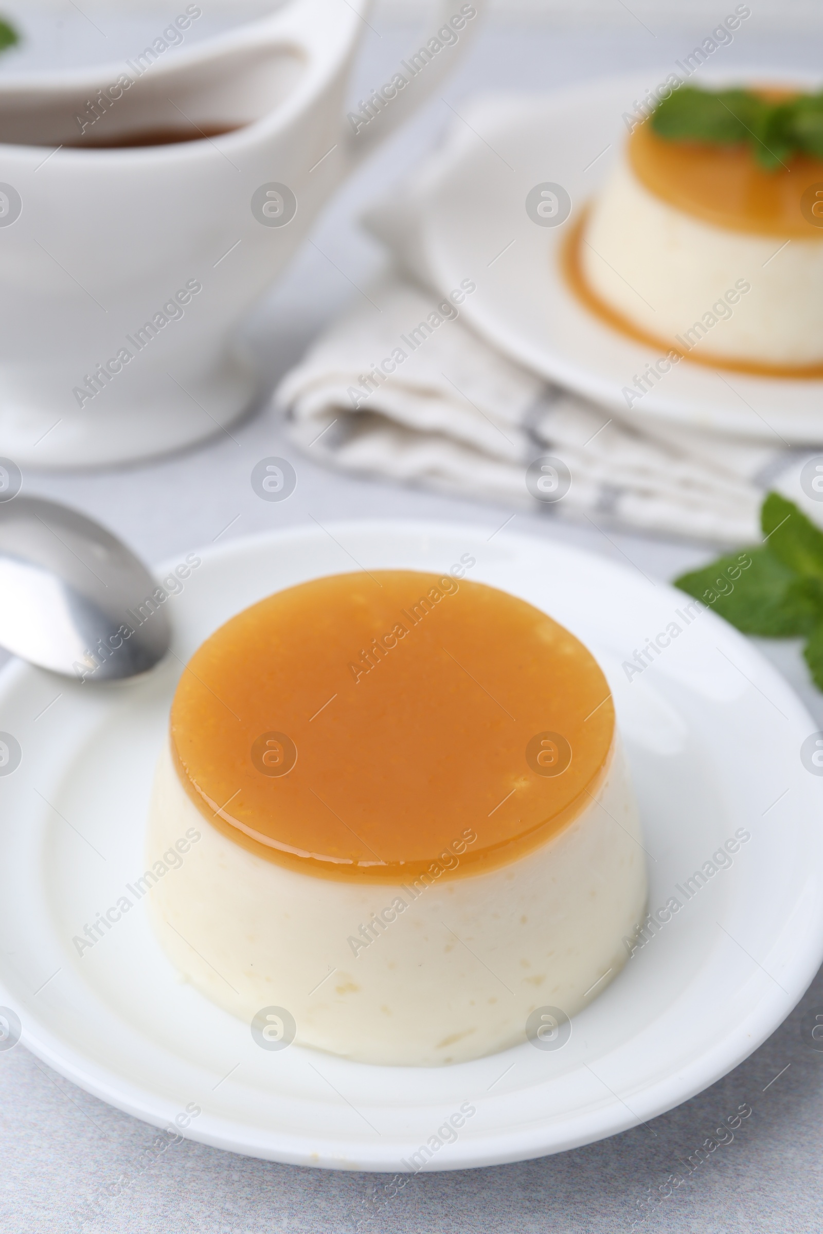 Photo of Tasty pudding with caramel sauce served on white table, closeup