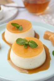 Photo of Tasty puddings with caramel sauce served on white table, closeup