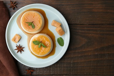 Photo of Tasty puddings with caramel sauce served on wooden table, flat lay. Space for text