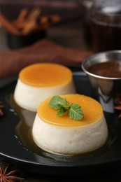 Photo of Tasty puddings with caramel sauce served on wooden table, closeup