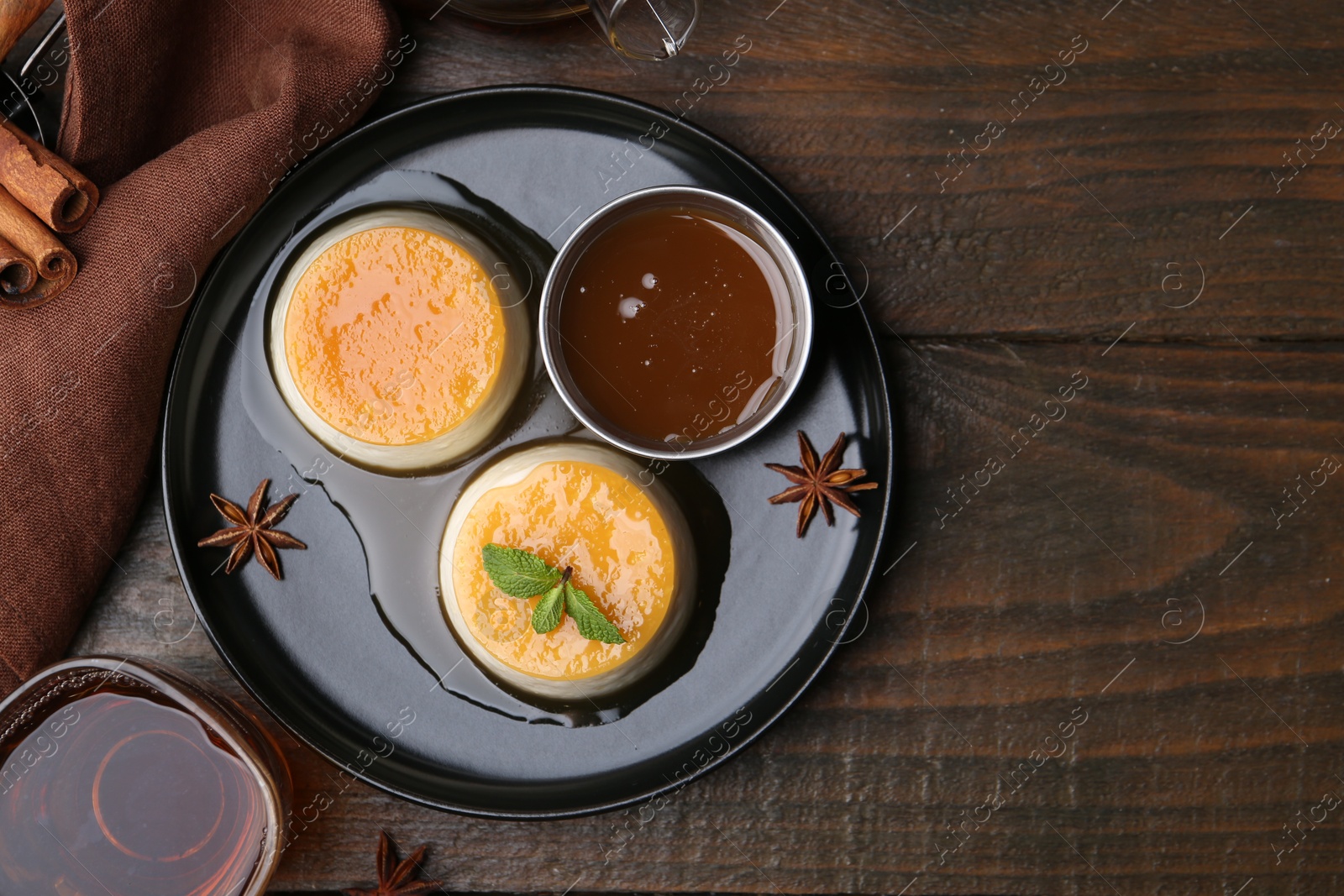 Photo of Tasty puddings with caramel sauce served on wooden table, flat lay. Space for text