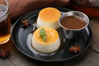 Photo of Tasty puddings with caramel sauce served on wooden table, closeup