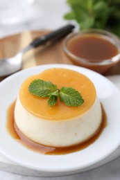 Photo of Tasty pudding with caramel sauce served on white marble table, closeup