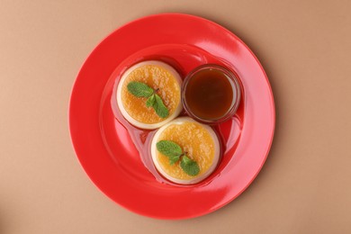 Photo of Tasty puddings with caramel sauce served on light brown background, top view