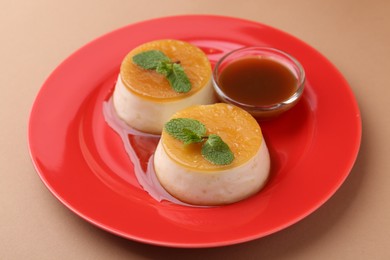 Photo of Tasty puddings with caramel sauce served on light brown background, closeup