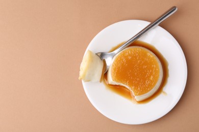 Photo of Tasty pudding with caramel sauce served on light brown background, top view. Space for text