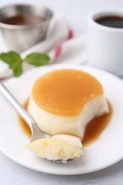 Photo of Tasty pudding with caramel sauce served on white textured table, closeup