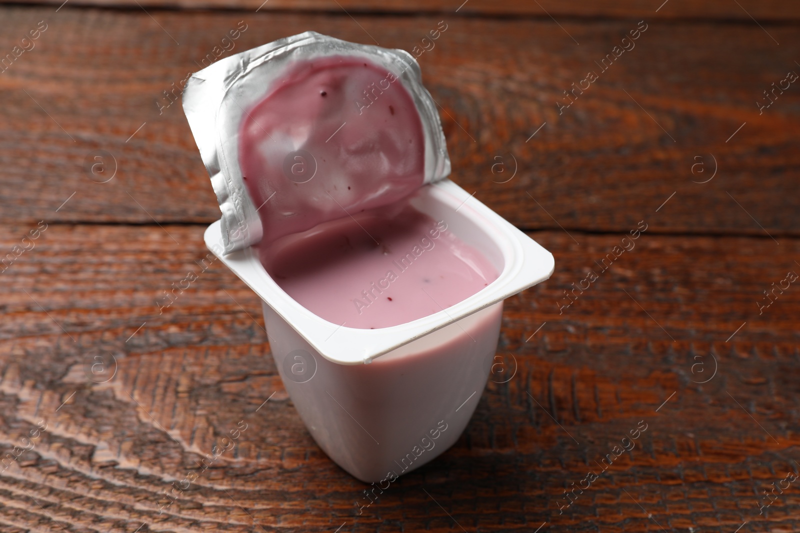 Photo of Delicious yogurt in plastic cup on wooden table, closeup