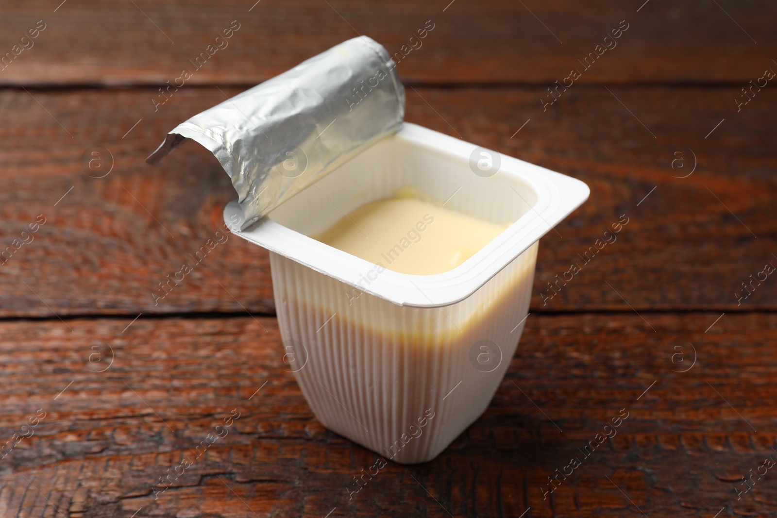 Photo of Delicious yogurt in plastic cup on wooden table, closeup