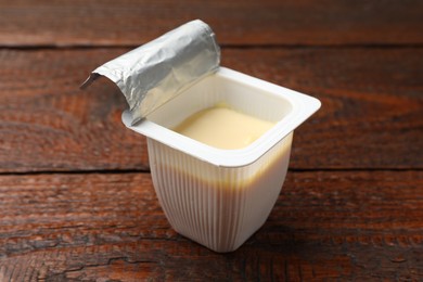 Photo of Delicious yogurt in plastic cup on wooden table, closeup