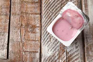 Photo of Delicious yogurt in plastic cup on wooden table, top view. Space for text