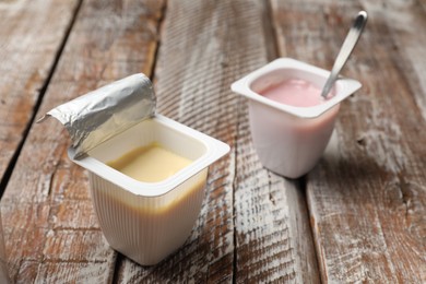 Photo of Delicious yogurts in plastic cups on wooden table, closeup