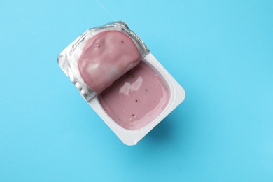 Photo of Delicious chocolate yogurt in plastic cup on light blue background, top view