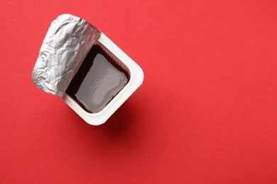 Photo of Delicious chocolate yogurt in plastic cup on red background, top view. Space for text