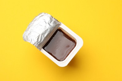 Photo of Delicious chocolate yogurt in plastic cup on yellow background, top view