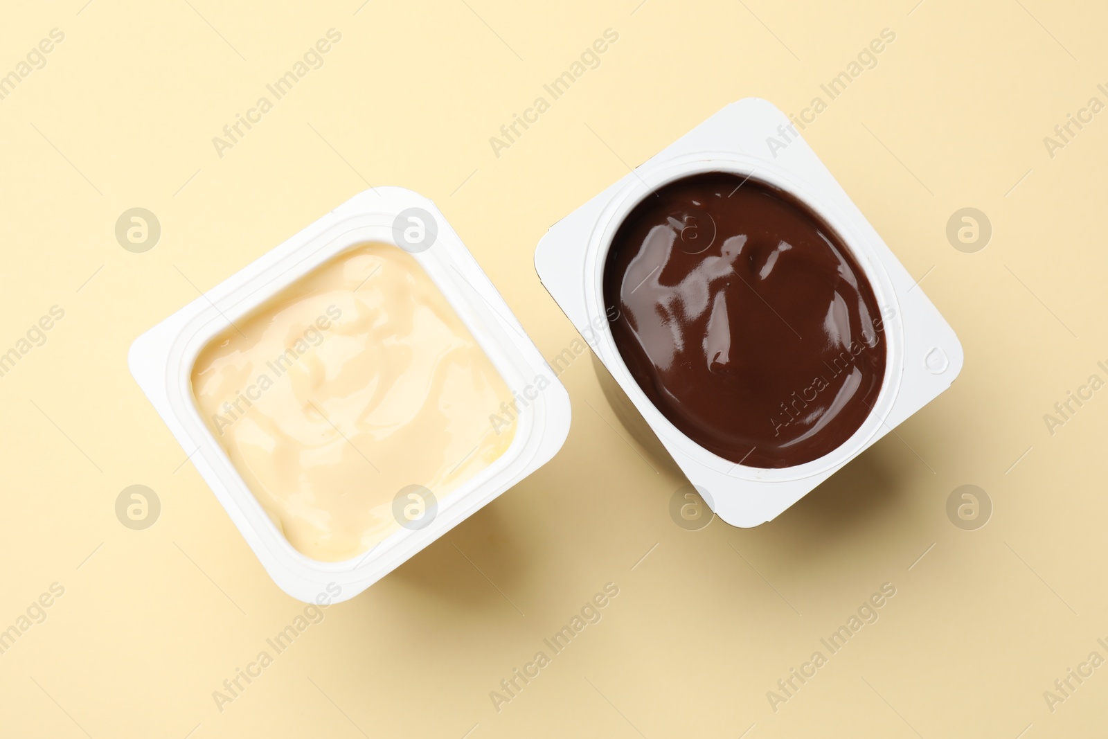 Photo of Delicious yogurts in plastic cups on yellow background, flat lay