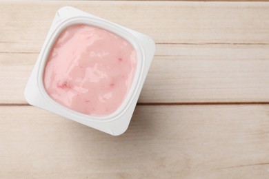 Photo of Delicious yogurt in plastic cup on wooden table, top view. Space for text