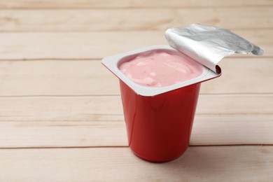 Photo of Delicious yogurt in plastic cup on wooden table, closeup. Space for text