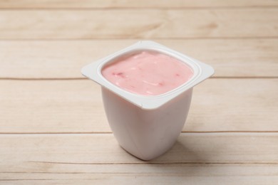 Photo of Delicious yogurt in plastic cup on wooden table, closeup