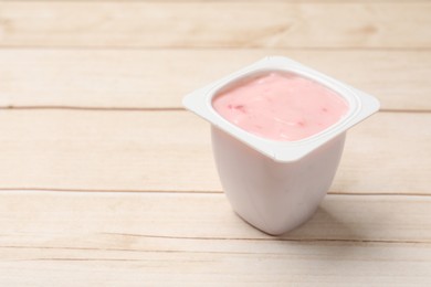 Photo of Delicious yogurt in plastic cup on wooden table, closeup. Space for text